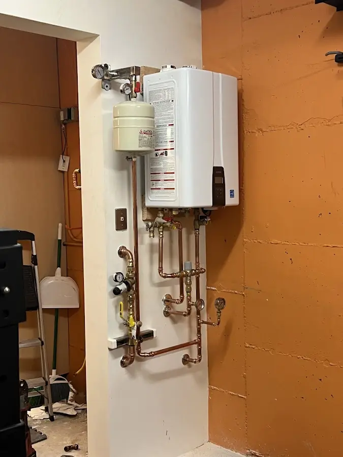 Plumbing technician inspecting water heater connections in Cedar Falls